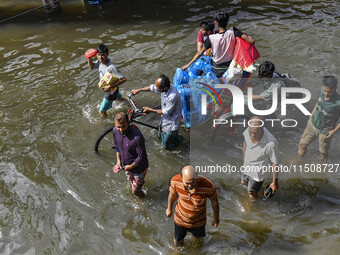 People wade through floodwaters in Feni district in Chittagong division, Bangladesh, on August 24, 2024. (