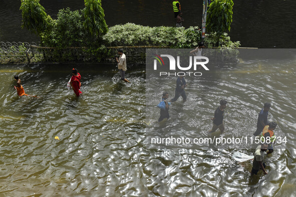 People wade through floodwaters in Feni district in Chittagong division, Bangladesh, on August 24, 2024. 