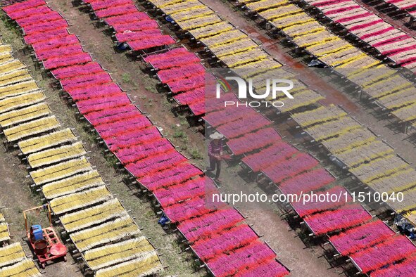 A worker dries incense on the drying field of a fragrance-making enterprise in Quanzhou, China, on August 25, 2024. 