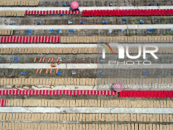 A worker dries incense on the drying field of a fragrance-making enterprise in Quanzhou, China, on August 25, 2024. (