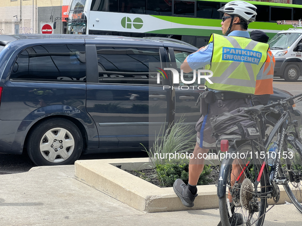 A parking enforcement officer issues parking tickets for illegal parking of cars on the side of the street in Toronto, Ontario, Canada, on A...