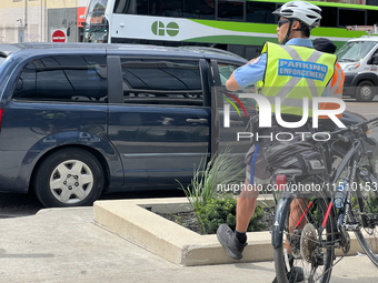 A parking enforcement officer issues parking tickets for illegal parking of cars on the side of the street in Toronto, Ontario, Canada, on A...