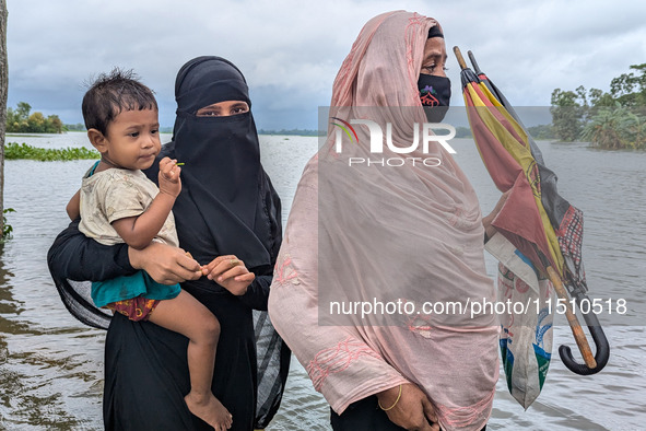 People wade through floodwaters in Feni, Bangladesh, on August 25, 2024. 