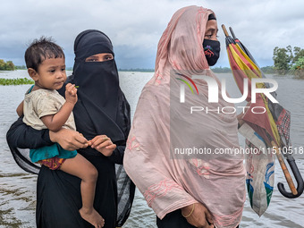 People wade through floodwaters in Feni, Bangladesh, on August 25, 2024. (