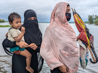 People wade through floodwaters in Feni, Bangladesh, on August 25, 2024. (