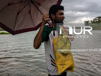 A man wades with his pet cat through floodwaters in Feni, Bangladesh, on August 25, 2024. (