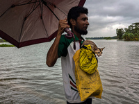 A man wades with his pet cat through floodwaters in Feni, Bangladesh, on August 25, 2024. (