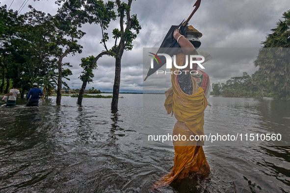 A woman wades through floodwaters in Feni, Bangladesh, on August 25, 2024. 