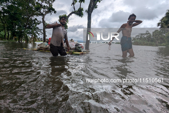 People wade through floodwaters in Feni, Bangladesh, on August 25, 2024. 