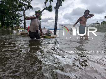 People wade through floodwaters in Feni, Bangladesh, on August 25, 2024. (