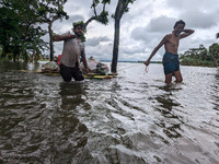 People wade through floodwaters in Feni, Bangladesh, on August 25, 2024. (