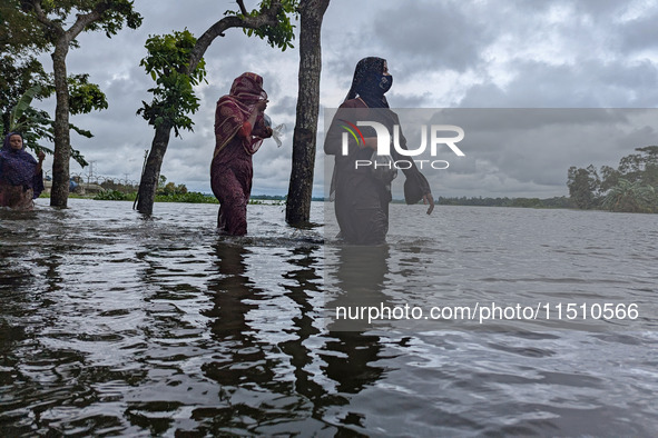 People wade through floodwaters in Feni, Bangladesh, on August 25, 2024. 