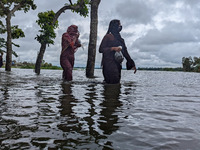 People wade through floodwaters in Feni, Bangladesh, on August 25, 2024. (