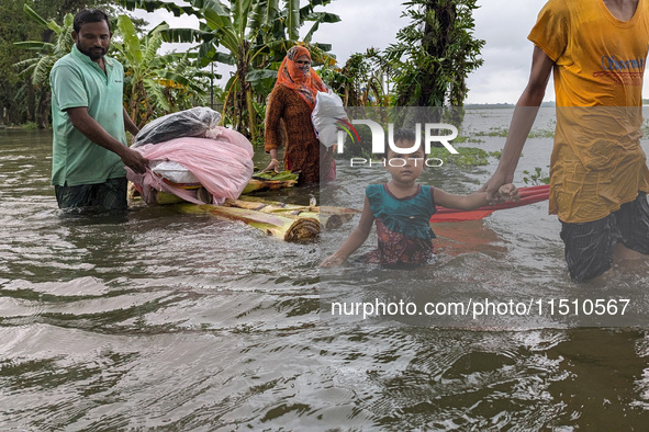 People wade through floodwaters in Feni, Bangladesh, on August 25, 2024. 