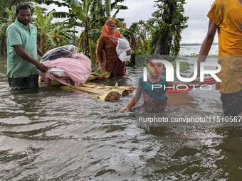 People wade through floodwaters in Feni, Bangladesh, on August 25, 2024. (