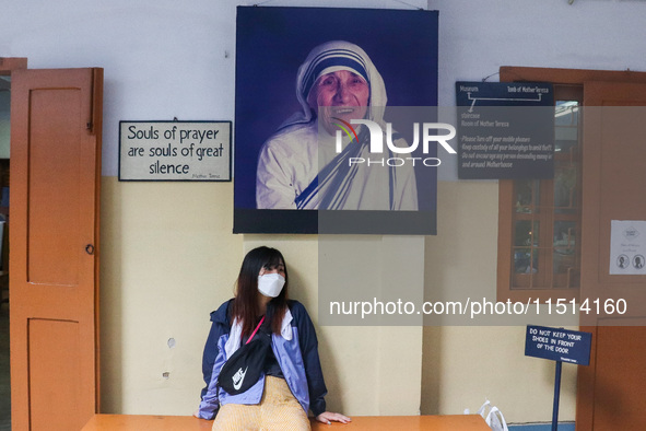 A lady wearing a mask stands in front of Saint Teresa's picture at Mother House in Kolkata, India, on August 26, 2024. 