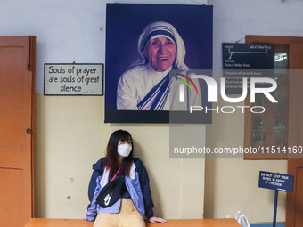 A lady wearing a mask stands in front of Saint Teresa's picture at Mother House in Kolkata, India, on August 26, 2024. (