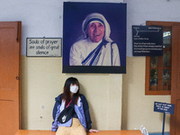 A lady wearing a mask stands in front of Saint Teresa's picture at Mother House in Kolkata, India, on August 26, 2024. (