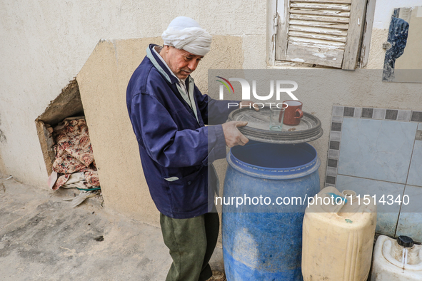 A man fills plastic jerry cans and barrels with drinking water at his home in a rural area in Kairouan, Tunisia, on May 8, 2024. As the regi...