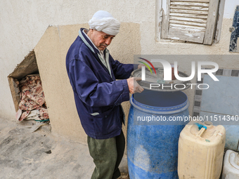 A man fills plastic jerry cans and barrels with drinking water at his home in a rural area in Kairouan, Tunisia, on May 8, 2024. As the regi...