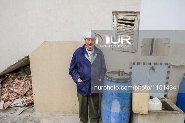 A man poses for pictures after filling plastic jerry cans and barrels with drinking water at his home located in a rural area in Kairouan, T...