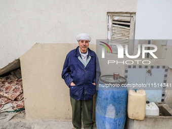 A man poses for pictures after filling plastic jerry cans and barrels with drinking water at his home located in a rural area in Kairouan, T...