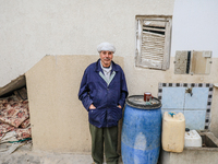 A man poses for pictures after filling plastic jerry cans and barrels with drinking water at his home located in a rural area in Kairouan, T...