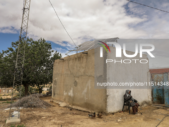 An older farmer sits by a water well whose motor is powered by photovoltaic energy to irrigate his field in a rural area in Kairouan, Tunisi...