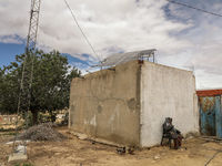 An older farmer sits by a water well whose motor is powered by photovoltaic energy to irrigate his field in a rural area in Kairouan, Tunisi...