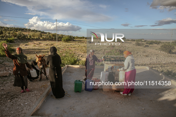 Rural women fill plastic cans with water at a drinking water point in the isolated rural area of Chrichira located in Kairouan, Tunisia, on...