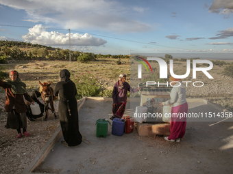 Rural women fill plastic cans with water at a drinking water point in the isolated rural area of Chrichira located in Kairouan, Tunisia, on...