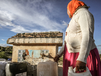 A rural woman fills plastic cans with water at a drinking water point in the isolated rural area of Chrichira located in Kairouan, Tunisia,...