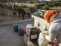 A rural woman fills plastic cans with water at a drinking water point in the isolated rural area of Chrichira located in Kairouan, Tunisia,...