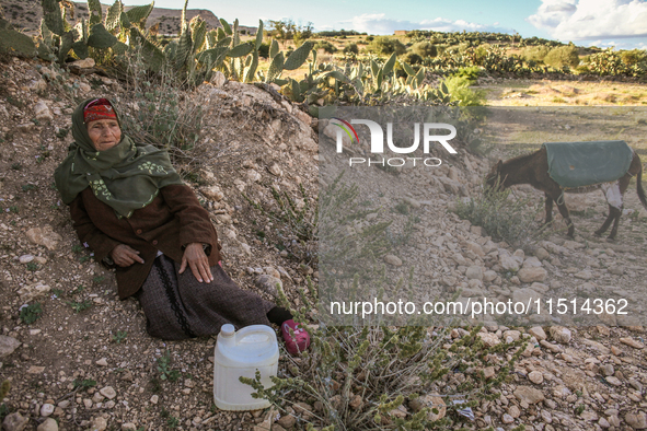 An elderly rural woman lies on the ground at a drinking water point in the isolated rural area of Chrichira in Kairouan, Tunisia, on May 8,...