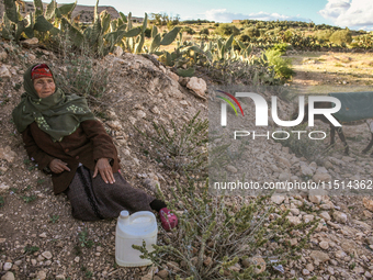 An elderly rural woman lies on the ground at a drinking water point in the isolated rural area of Chrichira in Kairouan, Tunisia, on May 8,...