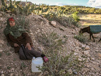 An elderly rural woman lies on the ground at a drinking water point in the isolated rural area of Chrichira in Kairouan, Tunisia, on May 8,...