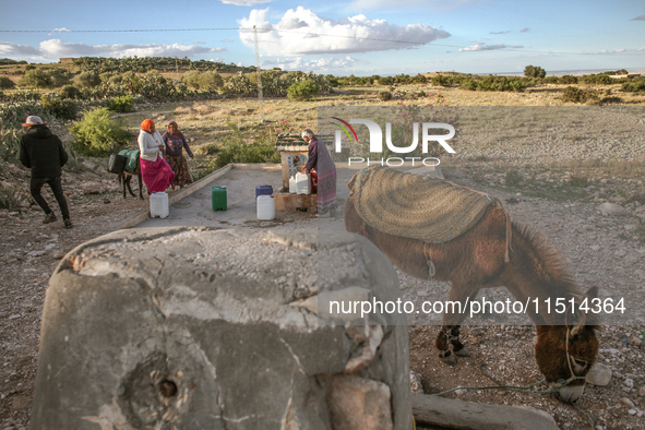 Rural women fill plastic cans with water at a drinking water point in the isolated rural area of Chrichira located in Kairouan, Tunisia, on...