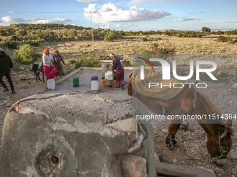 Rural women fill plastic cans with water at a drinking water point in the isolated rural area of Chrichira located in Kairouan, Tunisia, on...