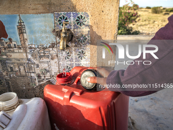 A rural woman fills plastic cans with water at a drinking water point in the isolated rural area of Chrichira located in Kairouan, Tunisia,...