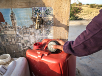 A rural woman fills plastic cans with water at a drinking water point in the isolated rural area of Chrichira located in Kairouan, Tunisia,...