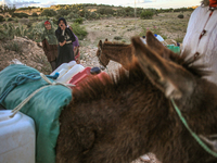 Rural women load jerry cans full of water on the back of a donkey at a drinking water point in the isolated rural area of Chrichira located...