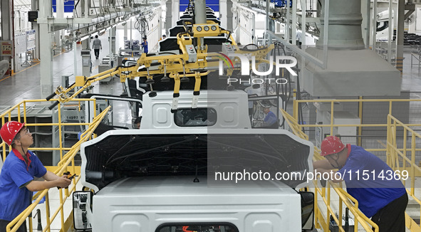 Workers work on an automobile production line at BYD Industrial Co LTD in Huai'an, China, on August 26, 2024. 