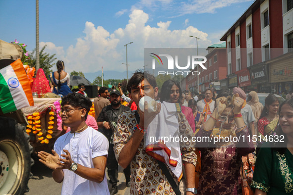 A Hindu devotee blows a conch shell as they celebrate the Janmashtami festival that marks the birthday of the Hindu god Krishna with a proce...