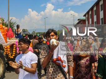 A Hindu devotee blows a conch shell as they celebrate the Janmashtami festival that marks the birthday of the Hindu god Krishna with a proce...