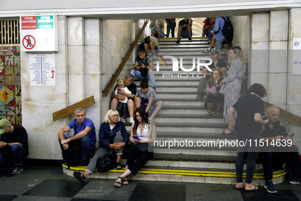 People sit on the steps of an interchange passage at the Khreshchatyk metro station during the massive Russian drone and missile attack on U...