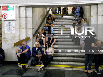 People sit on the steps of an interchange passage at the Khreshchatyk metro station during the massive Russian drone and missile attack on U...