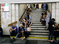 People sit on the steps of an interchange passage at the Khreshchatyk metro station during the massive Russian drone and missile attack on U...