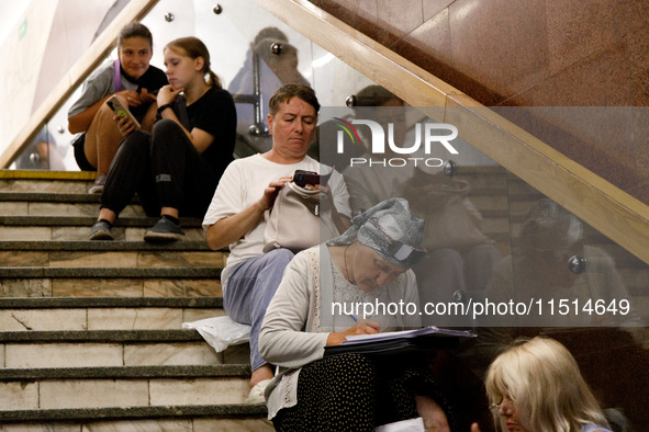 People sit on the steps of an interchange passage at the Teatralna metro station during the massive Russian drone and missile attack on Ukra...