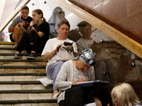 People sit on the steps of an interchange passage at the Teatralna metro station during the massive Russian drone and missile attack on Ukra...