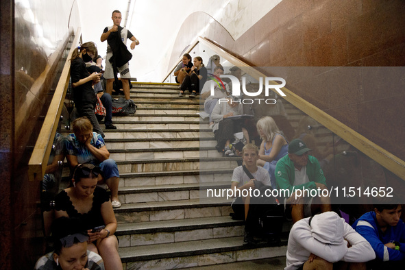 People sit on the steps of an interchange passage at the Teatralna metro station during the massive Russian drone and missile attack on Ukra...